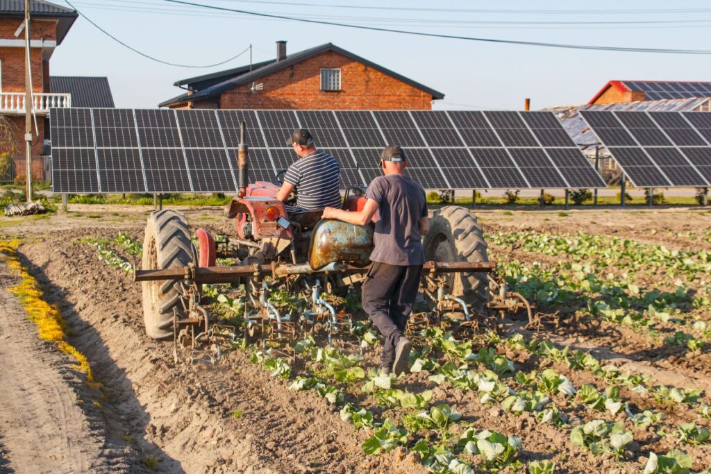 Landmænd med traktor ved solcelleanlæg på marken